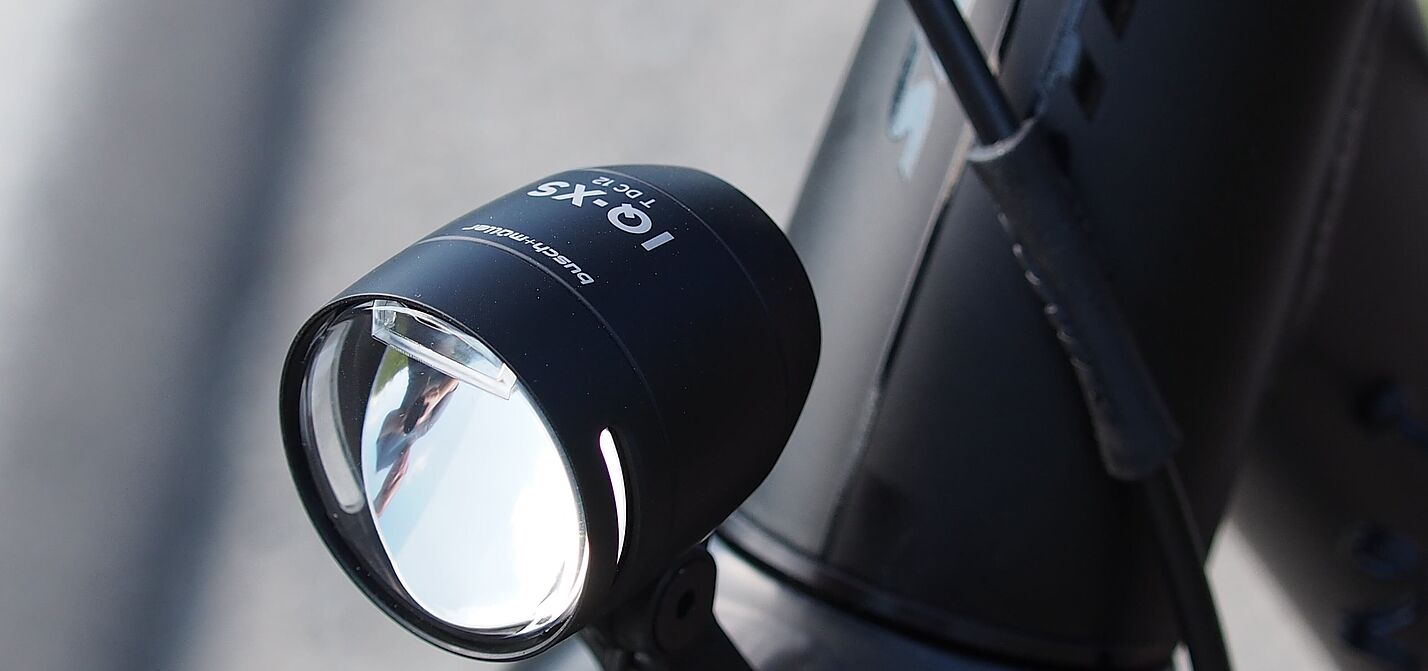 LED-Fahrradscheinwerfer Schwarzer LED-Fahrradscheinwerfer am silbernen Fahrradlenker montiert.